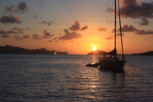 Sailing yacht at anchor in the Grenadines with the sunset behind.