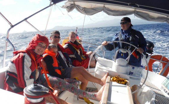 A family learning to sail wearing their lifejackets.